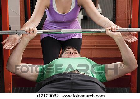 Stock Image - Man lifting weights in gym. Fotosearch