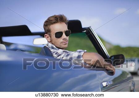 Stock Image - Man peering out of convertible. Fotosearch