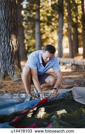 Man pitching a tent at campsite View Large Photo Image Stock Image - Man pitching a tent at campsite. Fotosearch