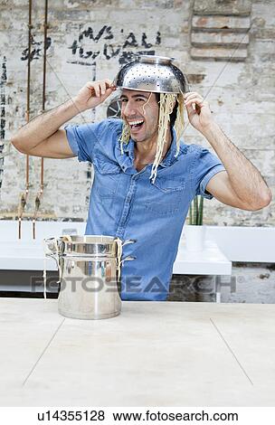 Stock Photo - Man playing with spaghetti in kitchen. Fotosearch