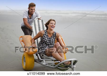 Man pushing girlfriend in cart on beach View Large Photo Image Stock Photo - Man pushing girlfriend in cart on beach. Fotosearch