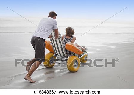 Man pushing girlfriend in cart on beach View Large Photo Image Stock Photo - Man pushing girlfriend in cart on beach. Fotosearch