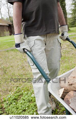 Man pushing wheelbarrow in backyard View Large Photo Image Stock Photography - Man pushing wheelbarrow in backyard. Fotosearch