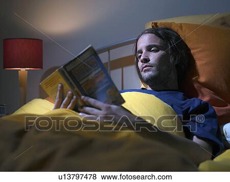Man reading a book in bed View Large Photo Image Stock Photo - Man reading a book in bed. Fotosearch
