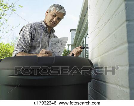 Stock Photograph - Man reading instructions in backyard. Fotosearch