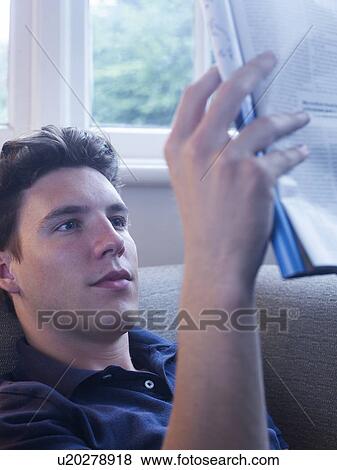 Stock Photo - Man reading newspaper on couch. Fotosearch