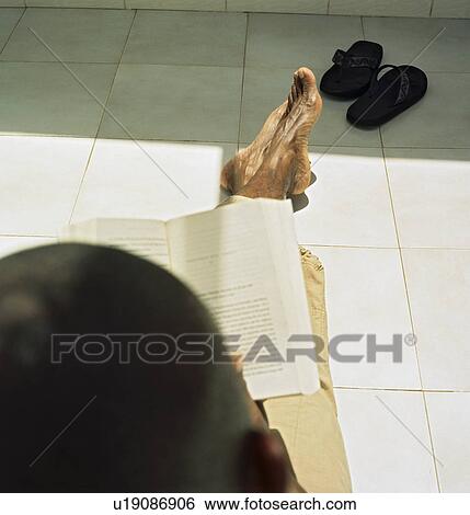 Stock Photograph - Man reading on patio in sun. Fotosearch