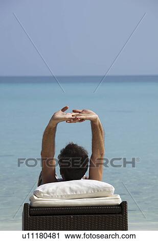 Man relaxing on daybed at tropical beach View Large Photo Image Stock Image - Man relaxing on daybed at tropical beach. Fotosearch