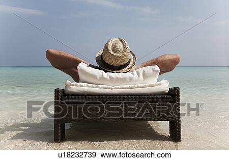 Man relaxing on daybed at tropical beach View Large Photo Image Stock Photo - Man relaxing on daybed at tropical beach. Fotosearch