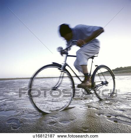 Man riding bicycle in wet sand on beach View Large Photo Image Stock Photo - Man riding bicycle in wet sand on beach. Fotosearch