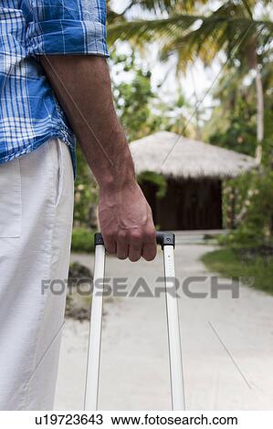 Man rolling suitcase in tropical resort View Large Photo Image Stock Image - Man rolling suitcase in tropical resort. Fotosearch