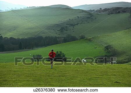 Stock Image - Man running in rural hills. Fotosearch