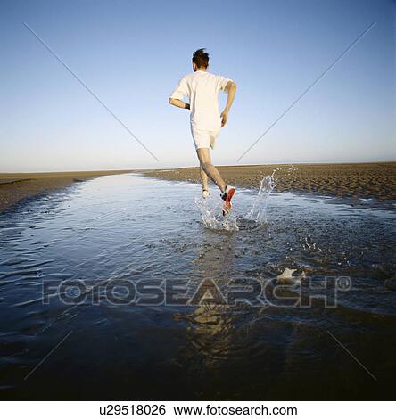 Man running in water on beach View Large Photo Image Stock Photograph - Man running in water on beach. Fotosearch