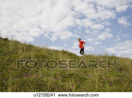 Man running up grassy hillside View Large Photo Image Stock Image - Man running up grassy hillside. Fotosearch