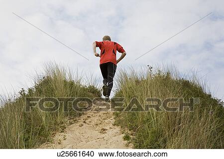 Man running up grassy hillside View Large Photo Image Stock Image - Man running up grassy hillside. Fotosearch