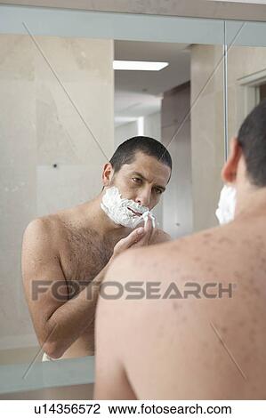 Stock Image - Man shaving in bathroom. Fotosearch
