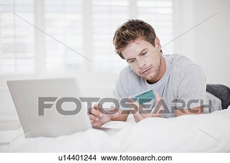 Man shopping online in bed View Large Photo Image Picture - Man shopping online in bed. Fotosearch