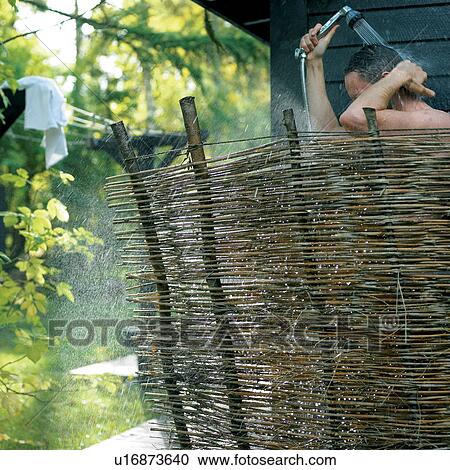 Stock Image - Man showering behind woven screen. Fotosearch