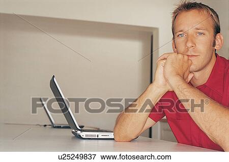 Man sitting at desk with laptops View Large Photo Image Stock Photo - Man sitting at desk with laptops. Fotosearch