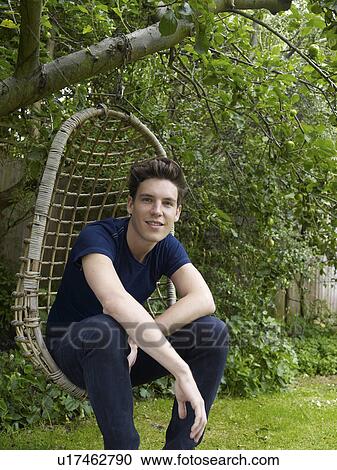 Man sitting in chair swing outdoors View Large Photo Image Stock Image - Man sitting in chair swing outdoors. Fotosearch