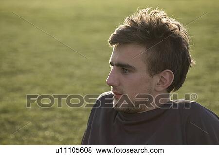 Stock Photo - Man sitting in grass. Fotosearch