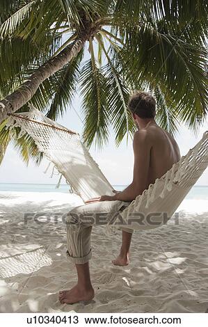 Man sitting in hammock on beach View Large Photo Image Stock Image - Man sitting in hammock on beach. Fotosearch