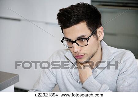 Picture - Man sitting in kitchen. Fotosearch