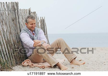 Man sitting in sand on beach View Large Photo Image Stock Photo - Man sitting in sand on beach. Fotosearch