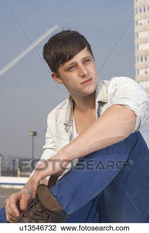 Stock Image - Man sitting on urban rooftop. Fotosearch