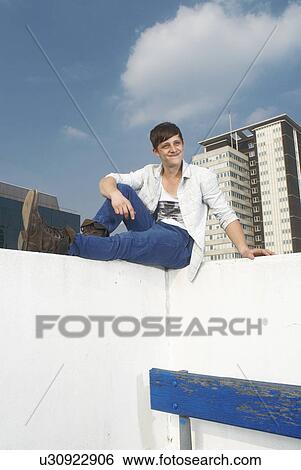 Stock Photograph - Man sitting on urban rooftop. Fotosearch