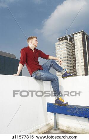Stock Photography - Man sitting on urban rooftop. Fotosearch