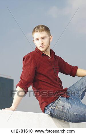 Stock Image - Man sitting on wall. Fotosearch