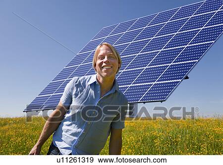Stock Photo - Man standing in field by solar panel. Fotosearch