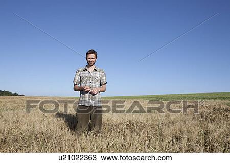 Man standing in wheat field View Large Photo Image Stock Image - Man standing in wheat field. Fotosearch