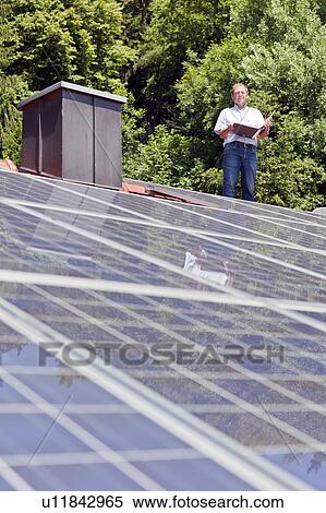 Man standing on solar paneled roof View Large Photo Image Stock Photography - Man standing on solar paneled roof. Fotosearch
