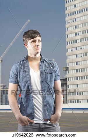 Stock Image - Man standing on urban rooftop. Fotosearch