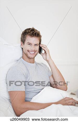 Man talking on cell phone in bed View Large Photo Image Stock Image - Man talking on cell phone in bed. Fotosearch
