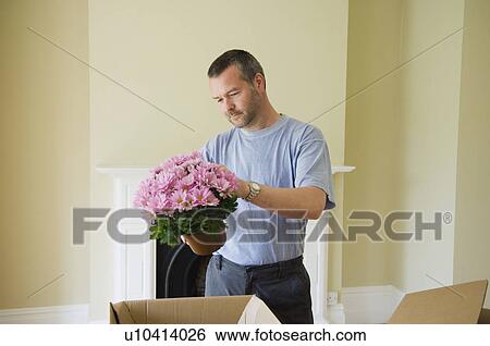Man unpacking flowers in new home View Large Photo Image Stock Photograph - Man unpacking flowers in new home. Fotosearch