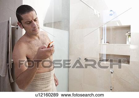 Stock Photo - Man using cell phone in bathroom. Fotosearch