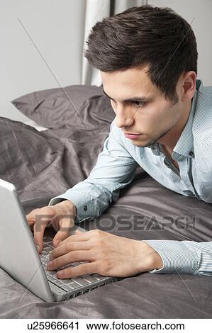 Man using laptop on bed View Large Photo Image Stock Image - Man using laptop on bed. Fotosearch