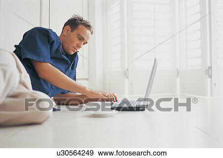 Man using laptop on floor View Large Photo Image Stock Photo - Man using laptop on floor. Fotosearch