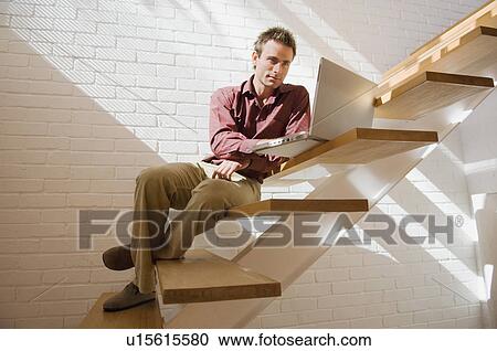 Stock Image - Man using laptop on steps. Fotosearch