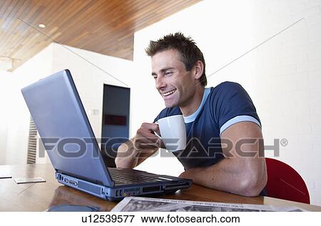 Man using laptop with cup of coffee View Large Photo Image Stock Photo - Man using laptop with cup of coffee. Fotosearch