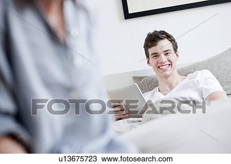 Stock Image - Man using tablet computer in bed. Fotosearch