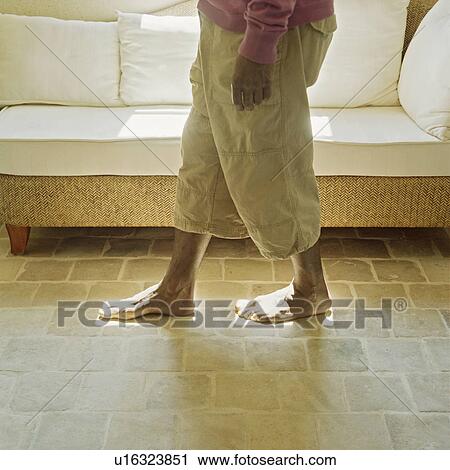 Stock Image - Man walking in sunlight from windows. Fotosearch