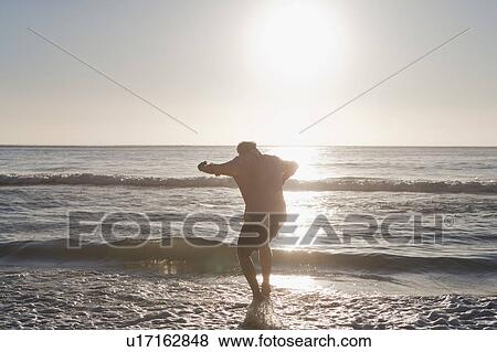 Man walking in water at beach View Large Photo Image Stock Photo - Man walking in water at beach. Fotosearch