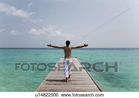 Stock Image - Man walking on deck overlooking sea. Fotosearch