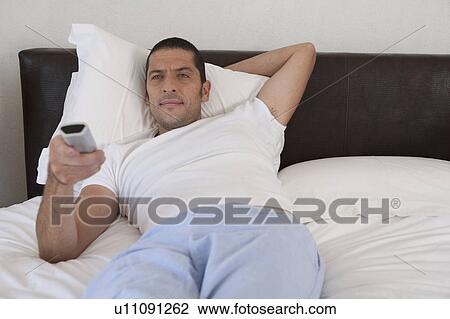 Man watching television in bed View Large Photo Image Stock Image - Man watching television in bed. Fotosearch