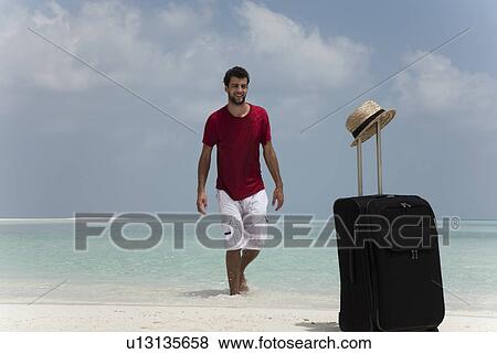 Man with rolling luggage on beach View Large Photo Image Stock Photo - Man with rolling luggage on beach. Fotosearch