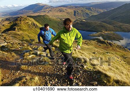 Stock Image - Men hiking on rocky mountainside. Fotosearch
